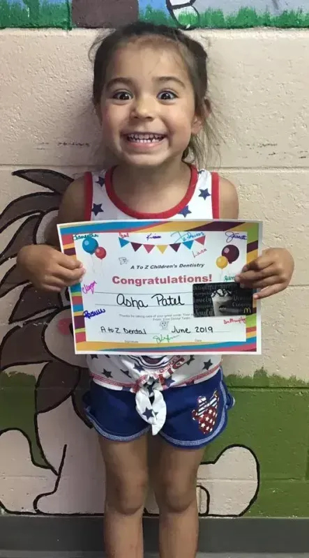 Girl in patriotic outfit smiles, holding a 