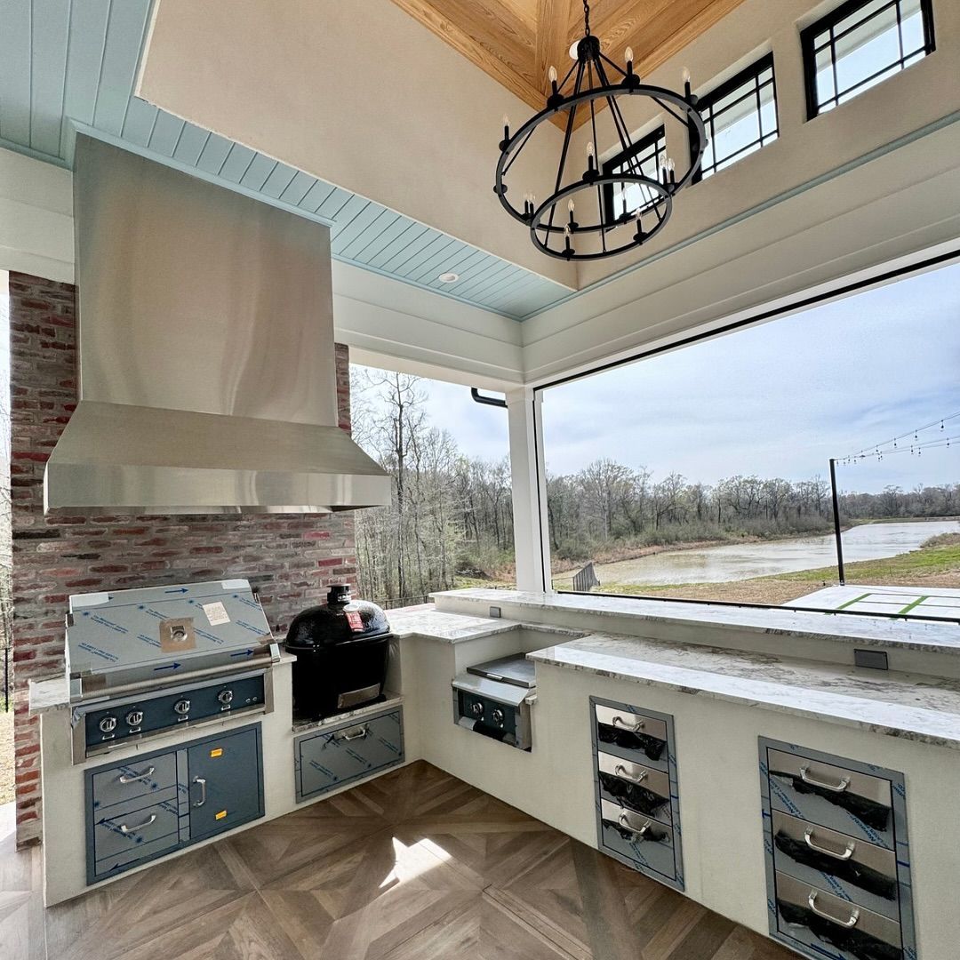Outdoor kitchen with grill, cabinets, and a view of a river.