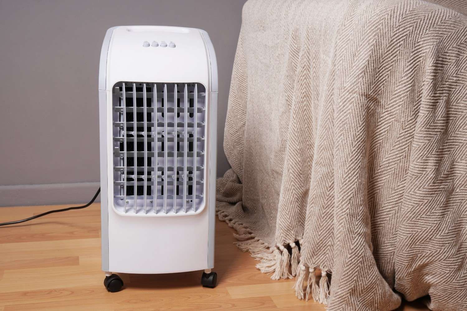 White Portable Air Cooler on Wheels Next to A Beige Blanket— Messina Air Conditioning & Electrical in Kuranda, QLD