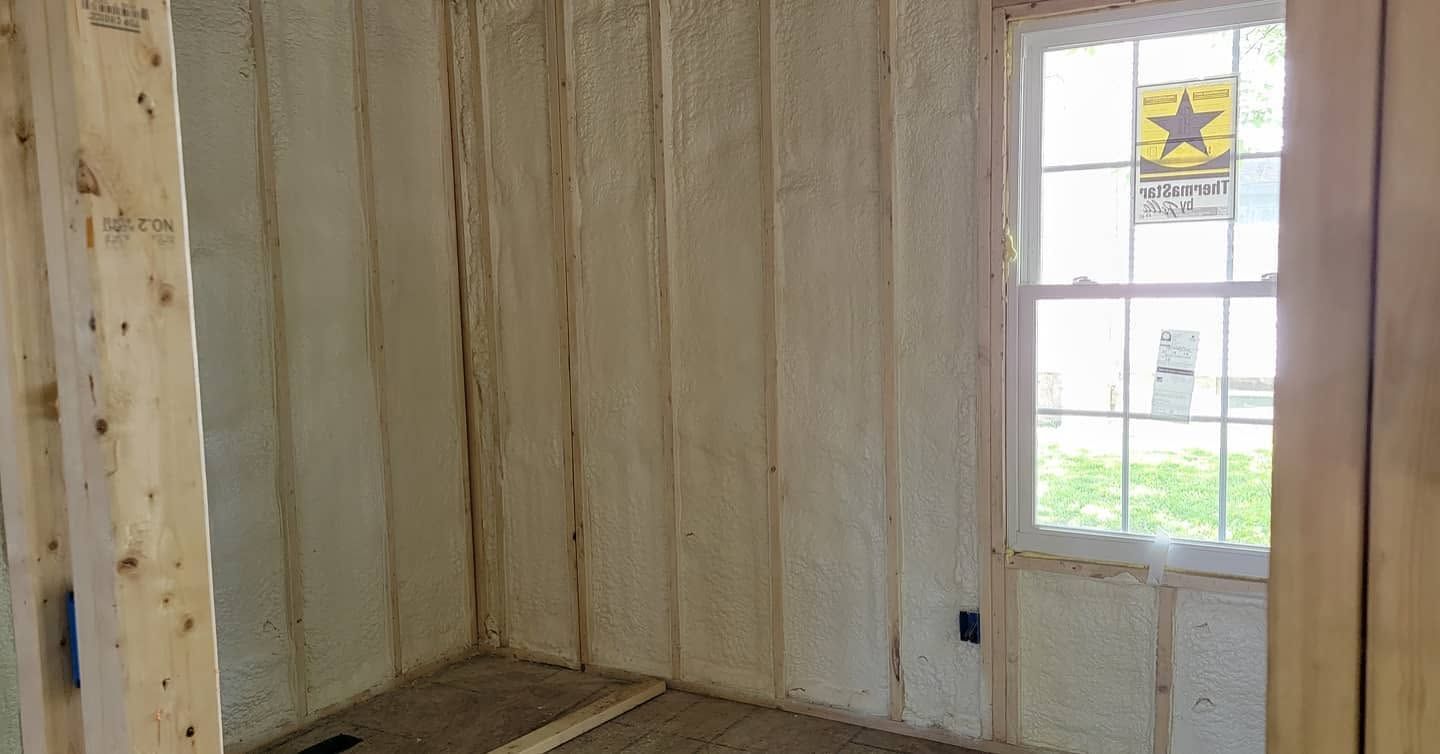 Unfinished room with insulated walls, wood framing, and a white door with a window.