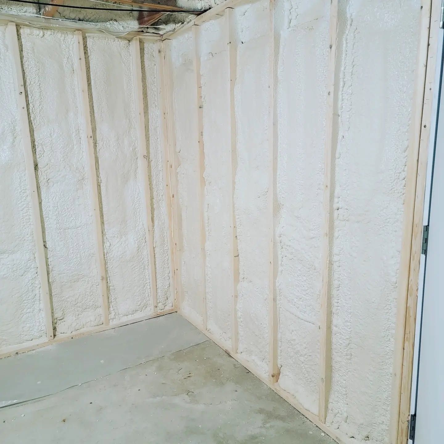 White paneled corner of an empty room with visible stains and peeling paint on the walls and floor