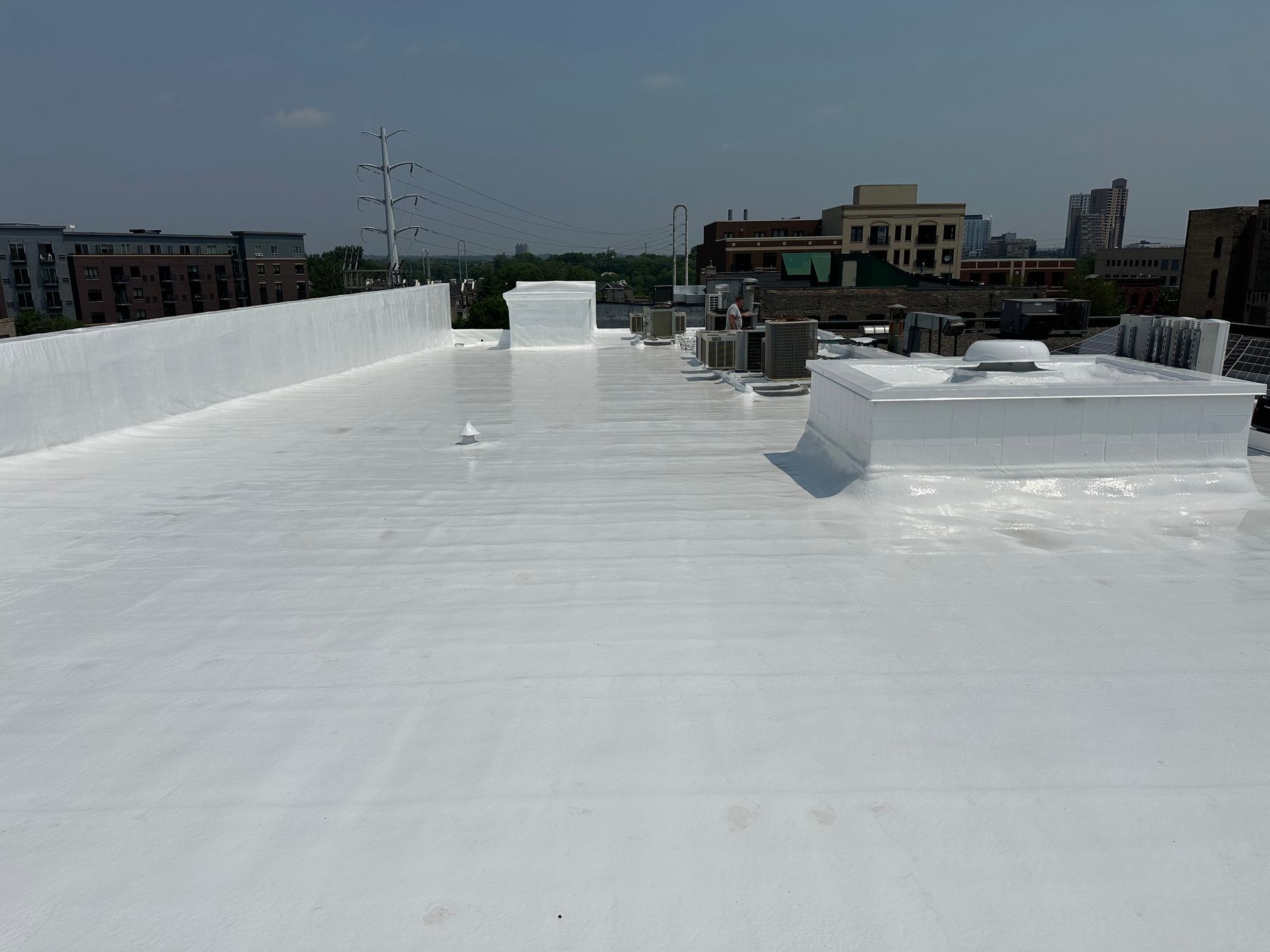 White rooftop with vents and low buildings under a clear sky
