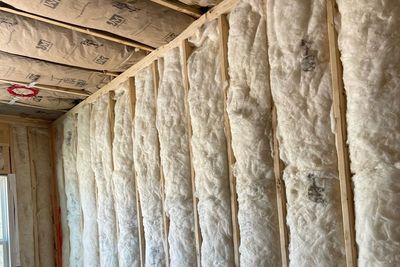 Insulated wall and ceiling cavity with exposed fiberglass batts and wood framing in a building under construction