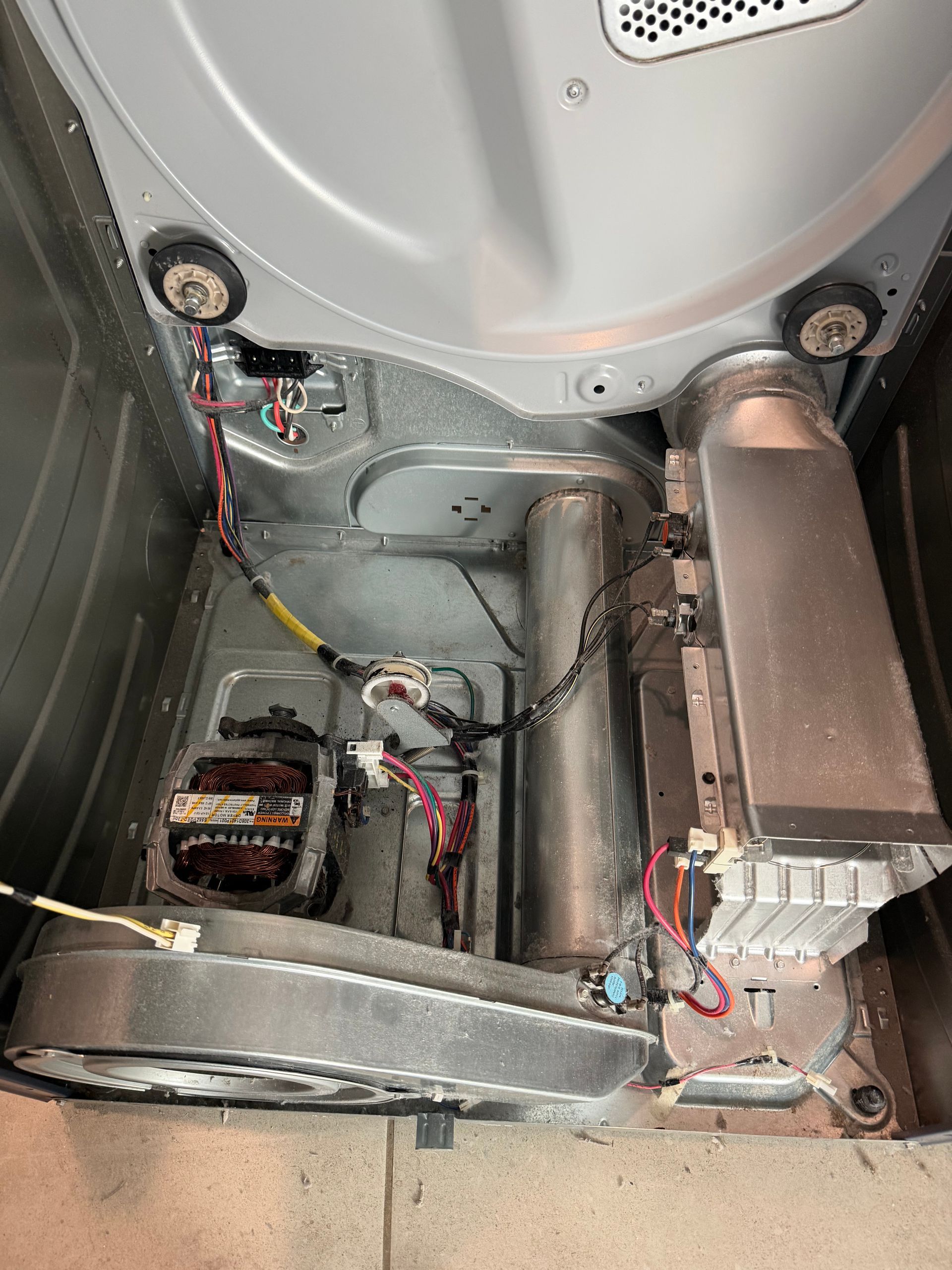 Inside a washer cabinet, exposed wiring and a motor assembly are visible during repair.