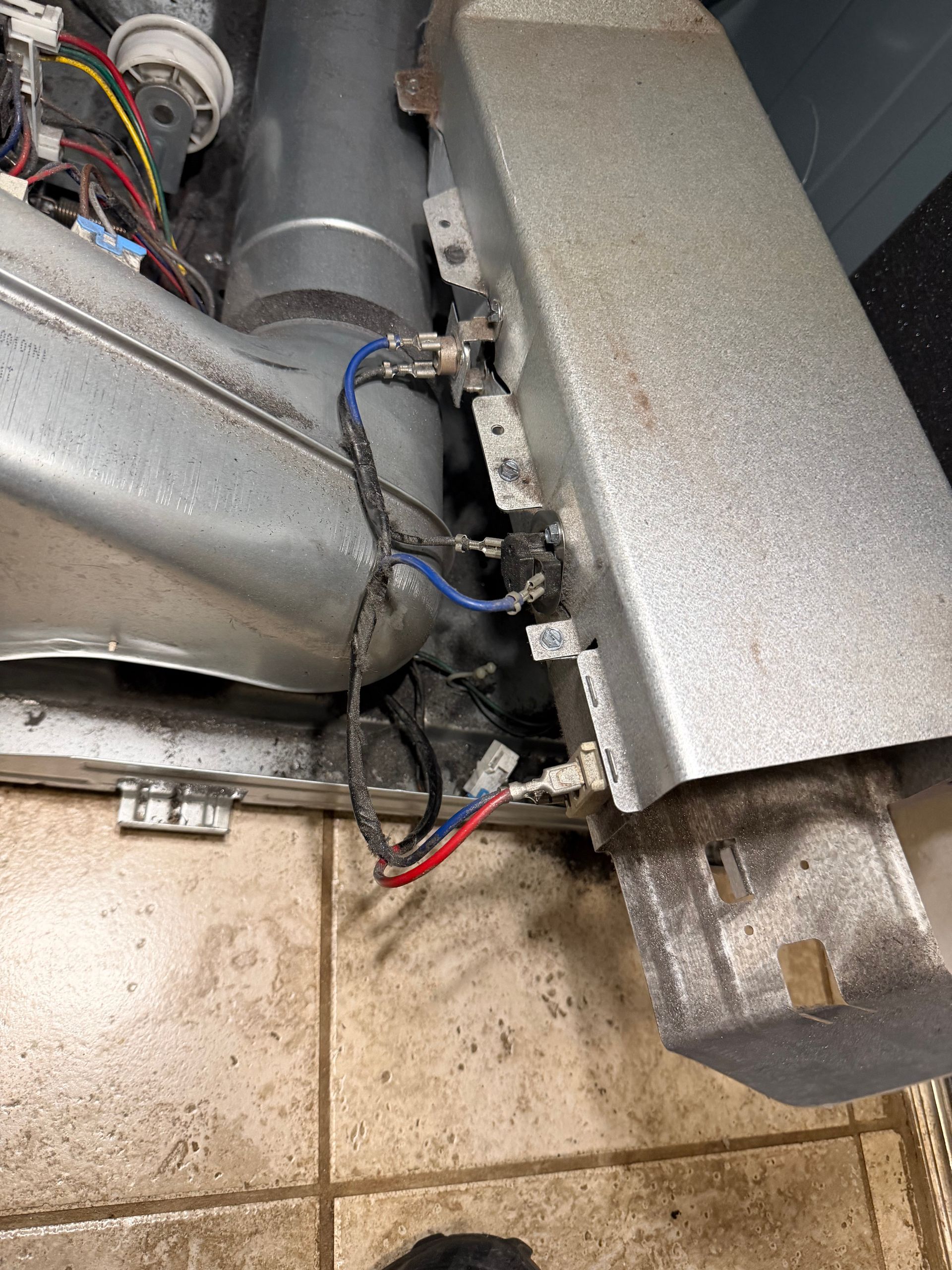 Close-up of exposed HVAC wiring and metal ductwork near a tiled floor inside a mechanical room