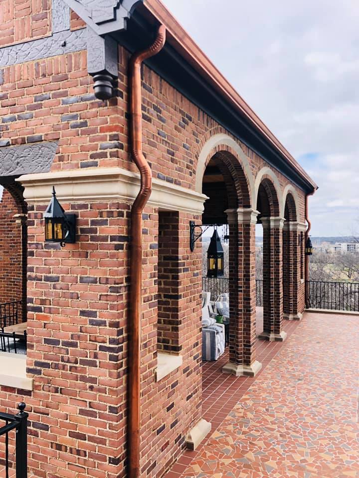 a brick building with arches and a copper gutter