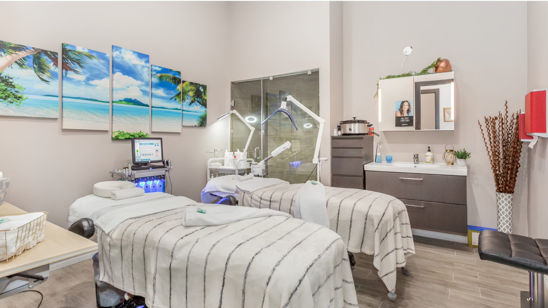 Modern spa room with massage tables, ocean wall art, and treatment equipment