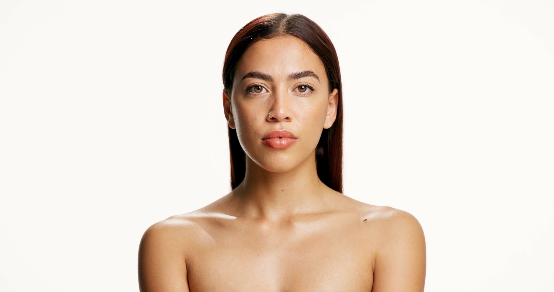 Portrait of a person with long dark hair against a light background, looking straight ahead.
