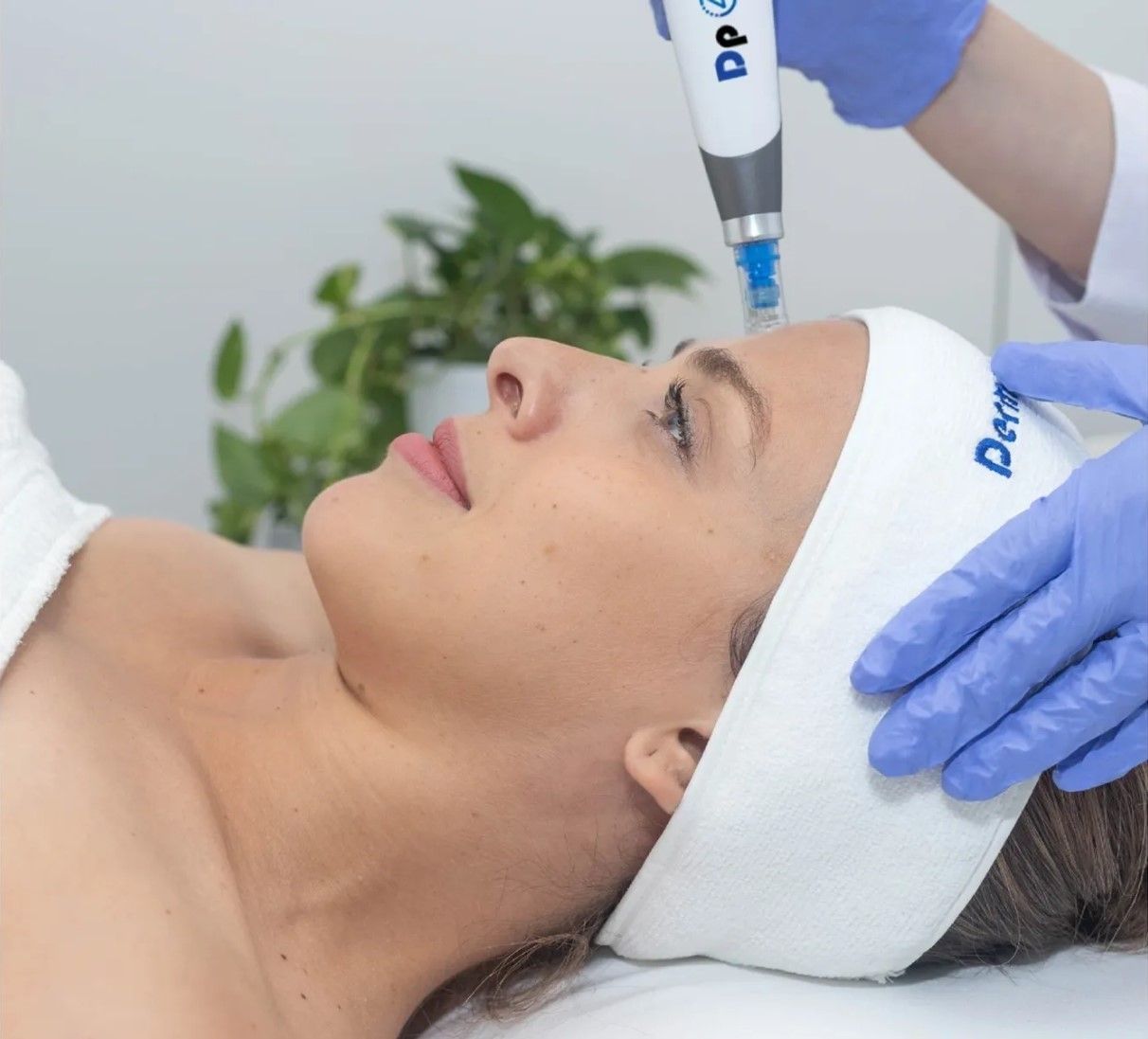 Cosmetic facial treatment with a gloved practitioner using a handheld device on a client’s forehead