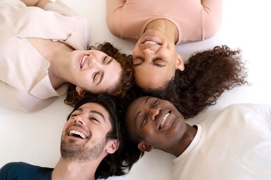 Three smiling people posing closely together against a beige background