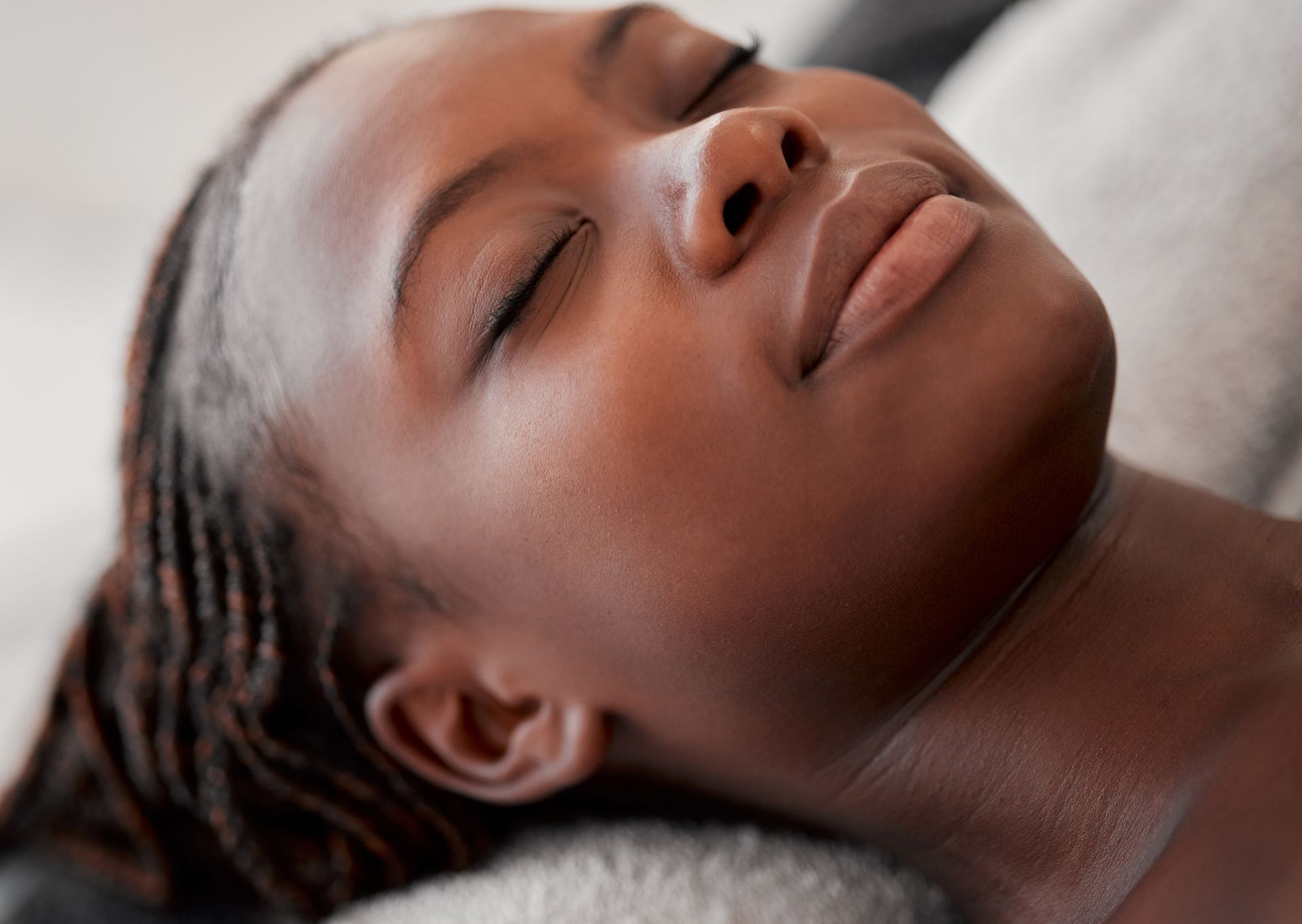 Close-up of a person resting with eyes closed on a soft gray blanket.