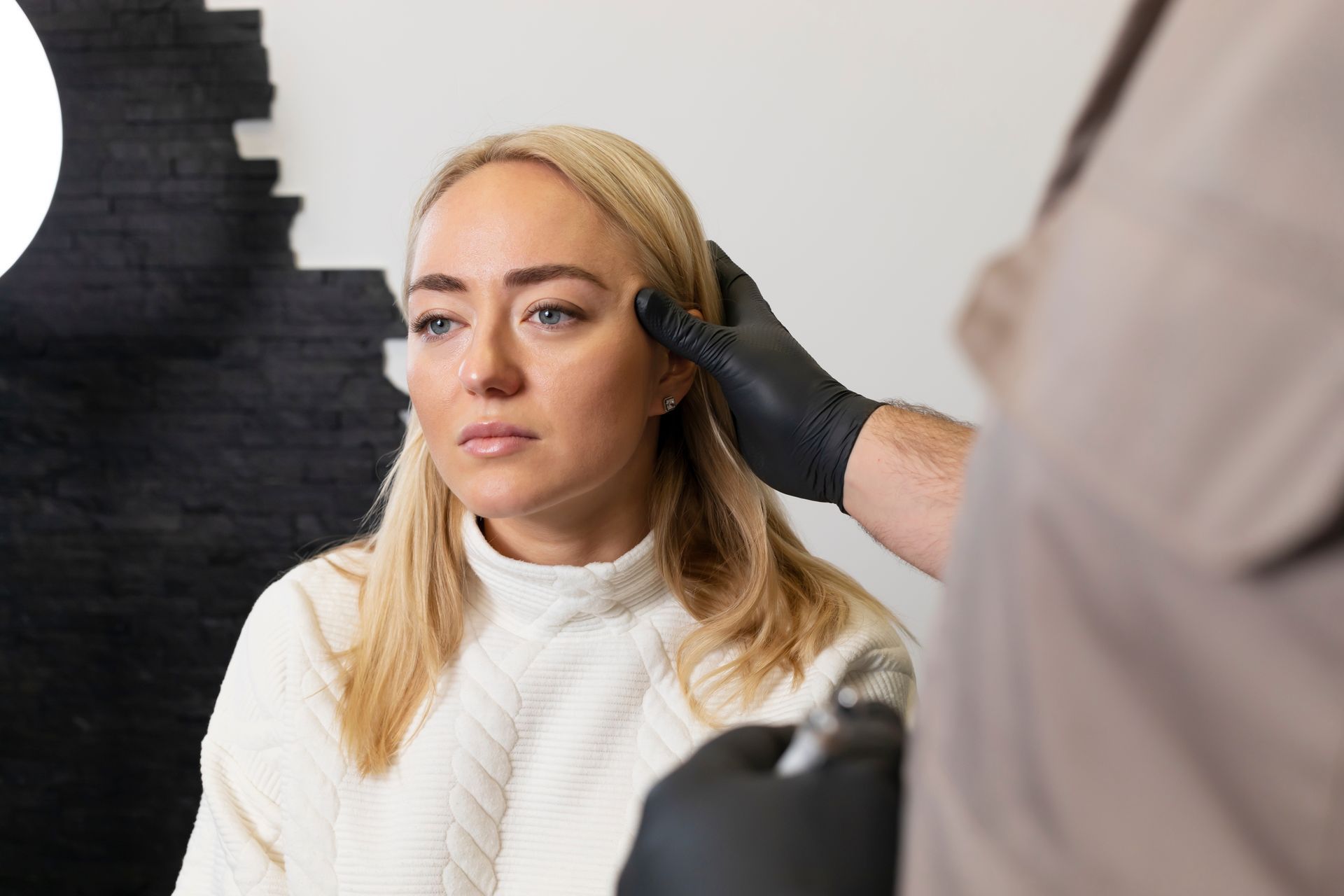Woman having her face examined by a clinician in a bright medical office