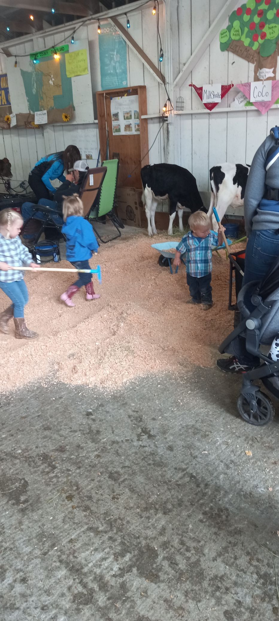 A group of children are playing with goats in a barn.