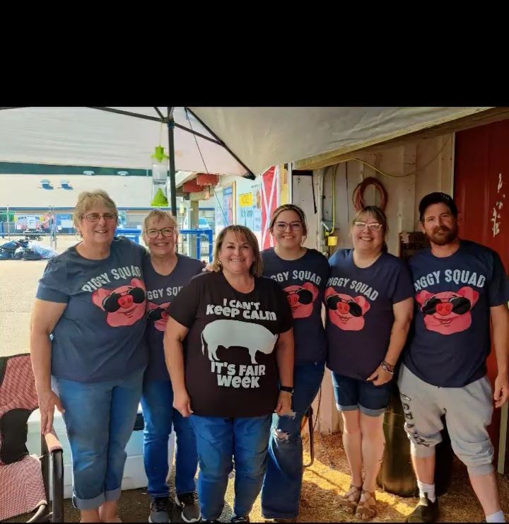 A group of people wearing pig squad shirts pose for a picture