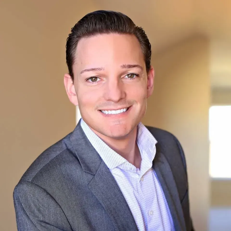 A man in a suit and white shirt is smiling for the camera.