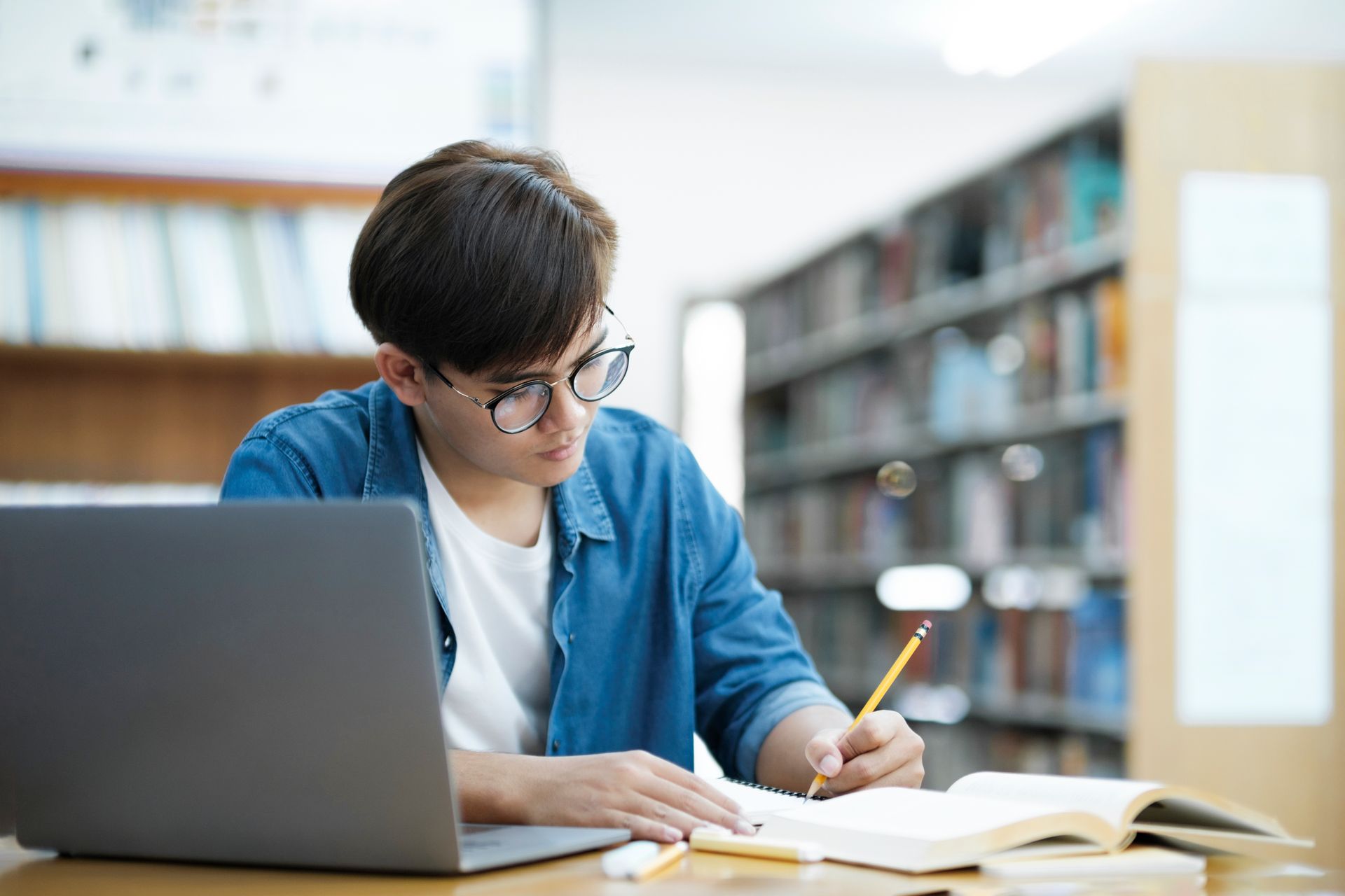 Woman sitting in yellow beanbag, reading a book. She wears a white shirt, black overalls, black boots, and striped socks.