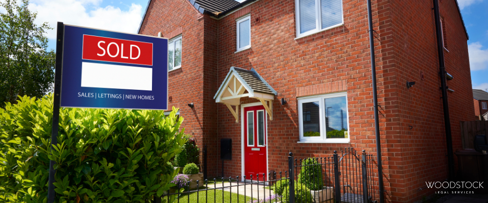 A modern red-brick semi-detached house with a bright red front door and small front garden, shown alongside a “Sold” estate agent sign indicating the property has been purchased.