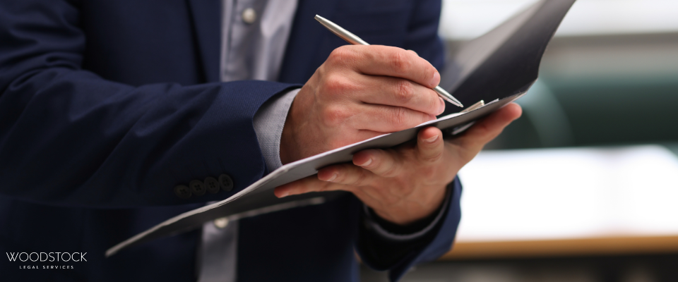 A professional in a suit writing notes on a clipboard, symbolising legal documentation