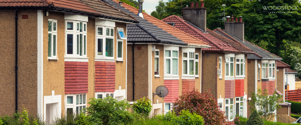 Row of terraced UK houses with red tiled bay windows and greenery, Woodstock Legal Services branding