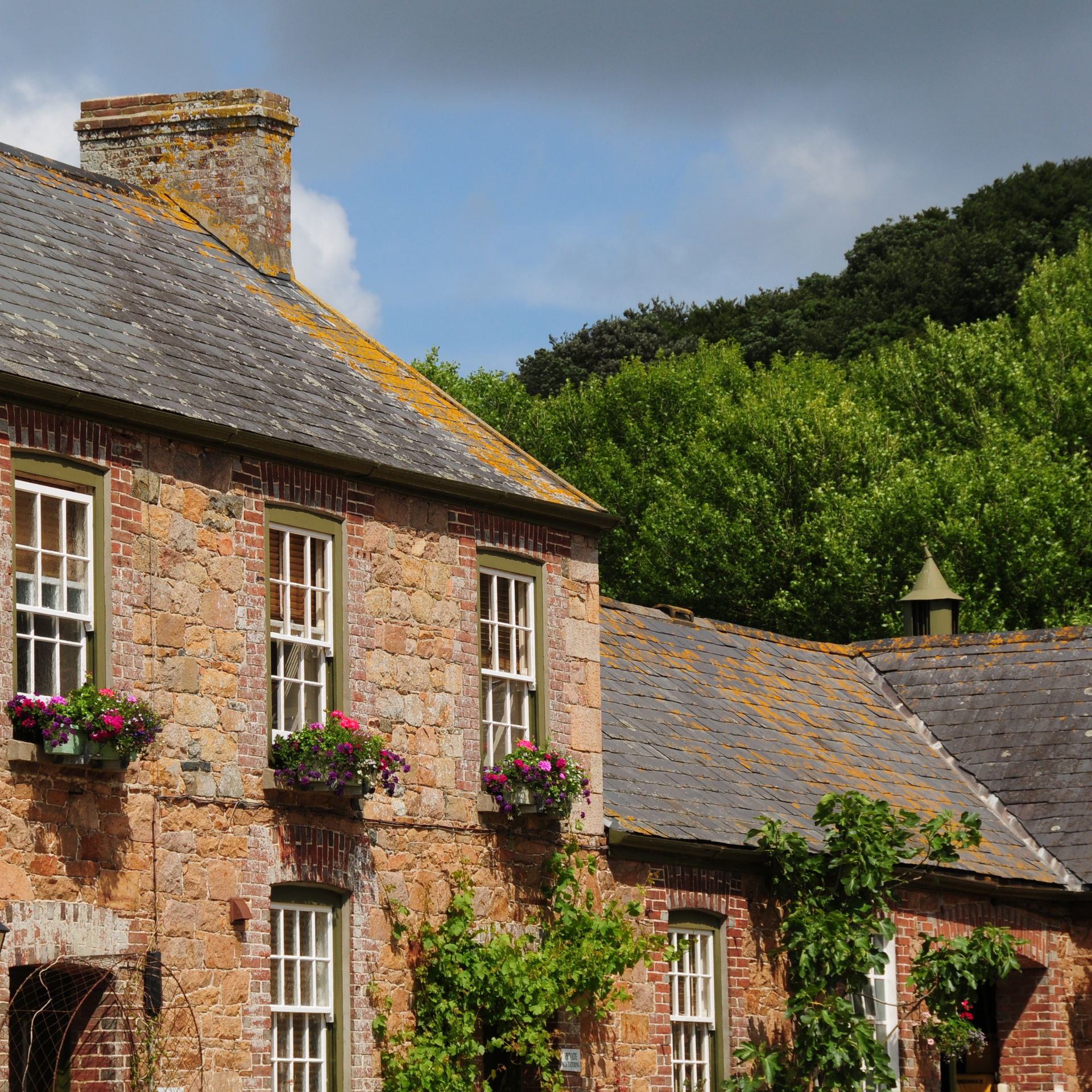 Rural stone farmhouse with window boxes and trees