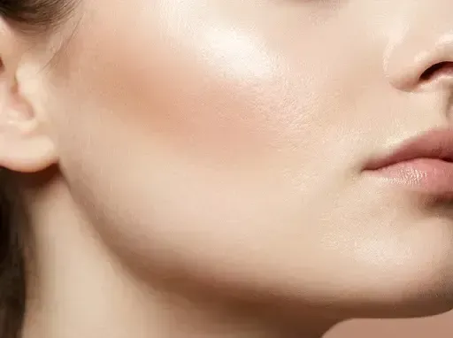Close-up of a person’s cheek and jawline with smooth, dewy skin and natural makeup