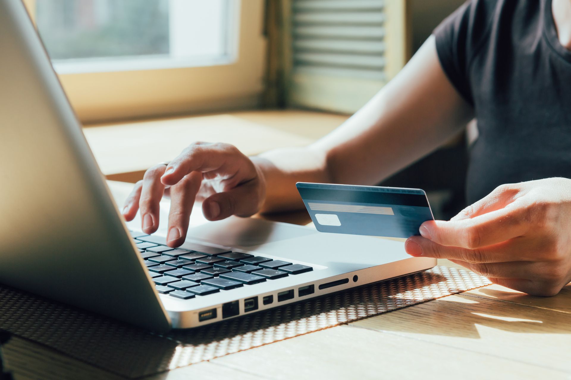 Person using a laptop and holding a credit card while shopping online