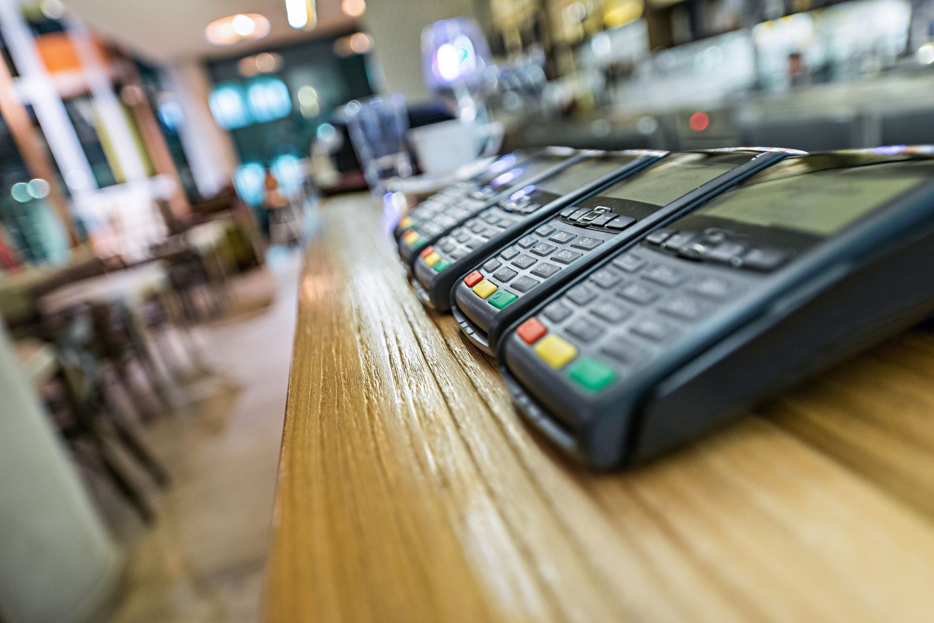 Credit card terminals lined up on a wooden counter in a blurred store setting