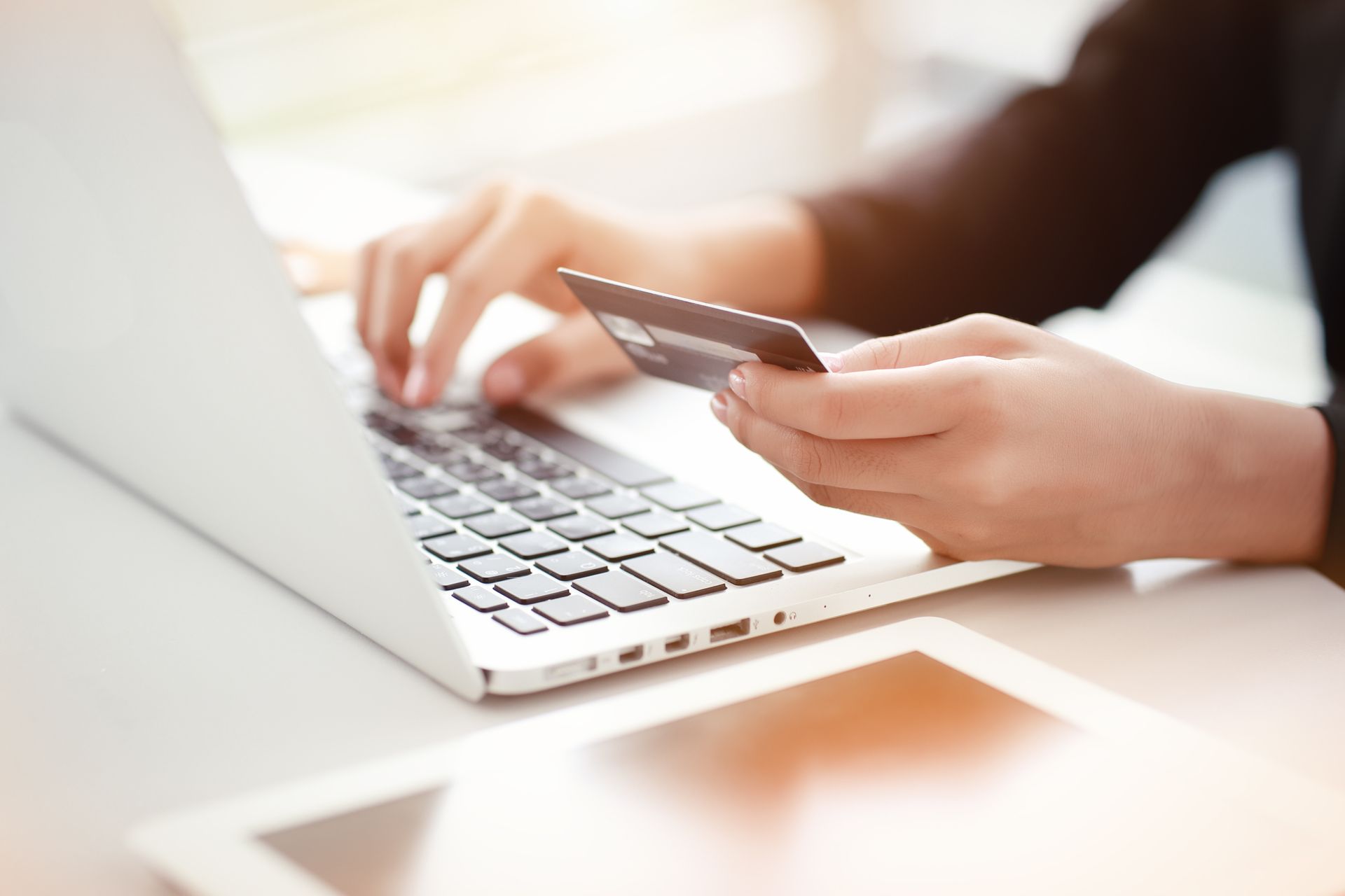 Hands using a credit card to shop online on a laptop