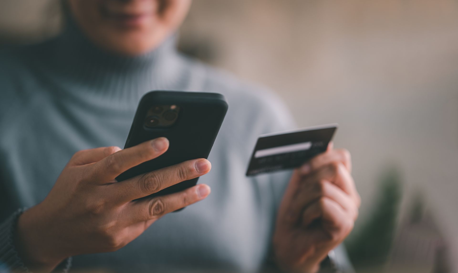 Person holding a smartphone and credit card, suggesting an online purchase or payment