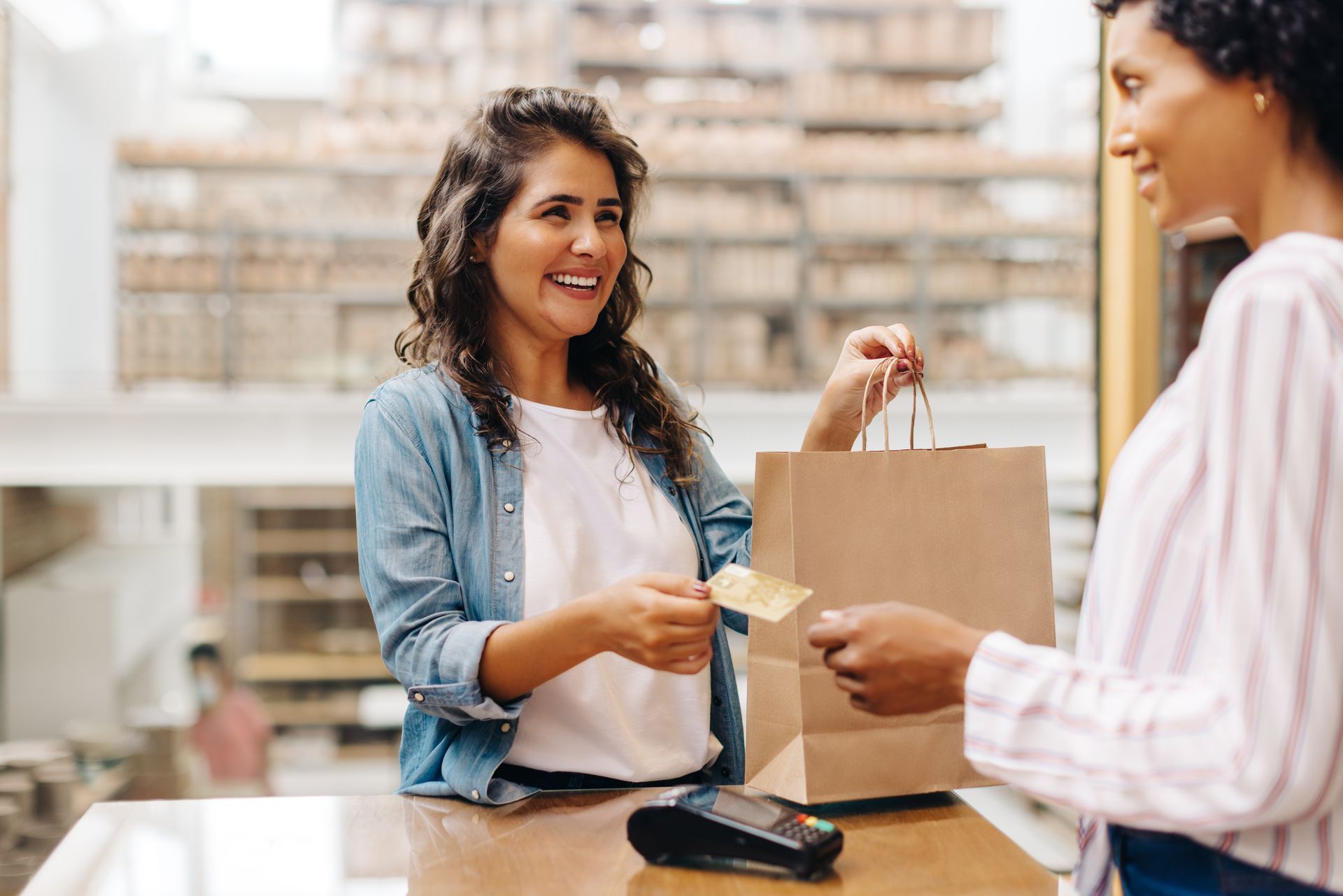 Customer paying at a checkout counter with a card while cashier hands over a bag