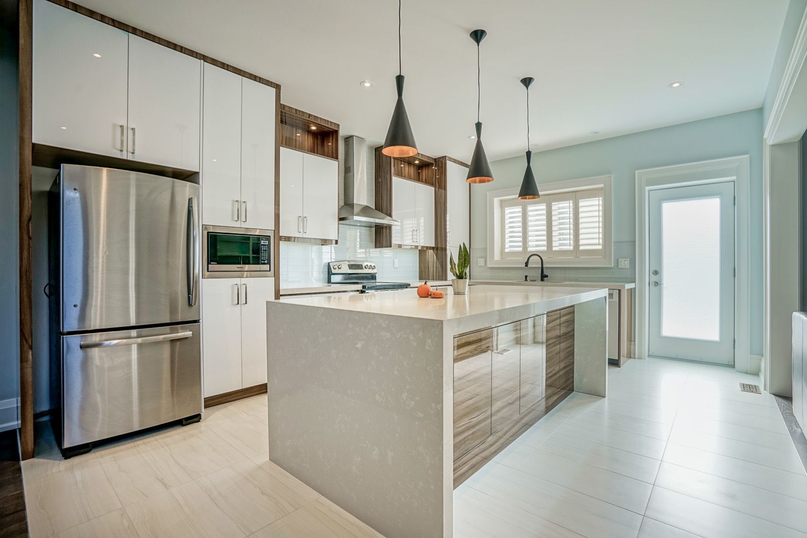 Bright modern kitchen with stainless steel appliances, white cabinets, island, and pendant lights