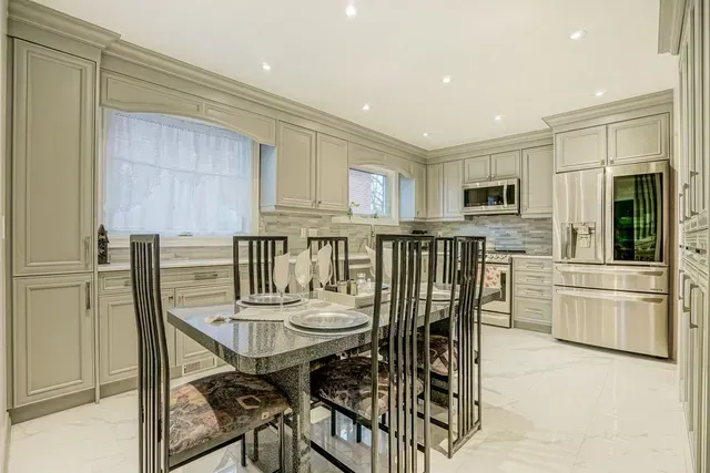 Gray kitchen with dining table, cabinetry, and stainless steel appliances.