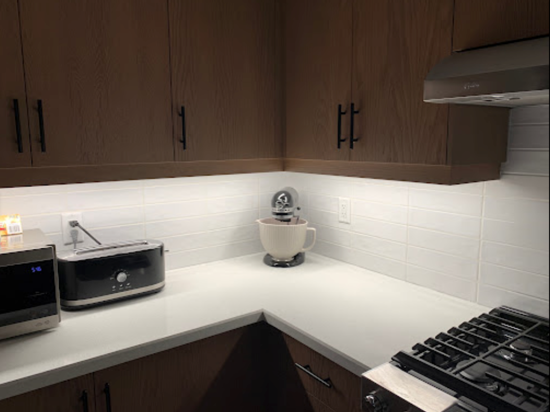 A kitchen with a stove , microwave , and blender on the counter.