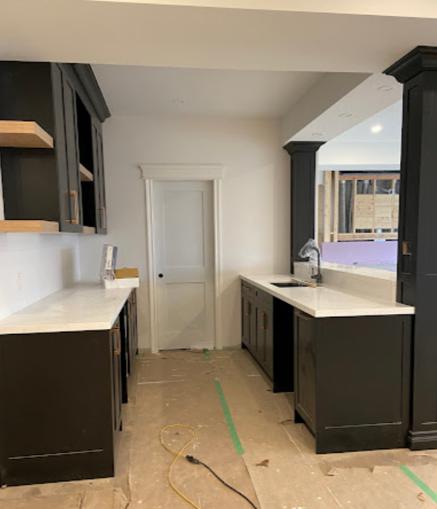 A kitchen with black cabinets and white counter tops
