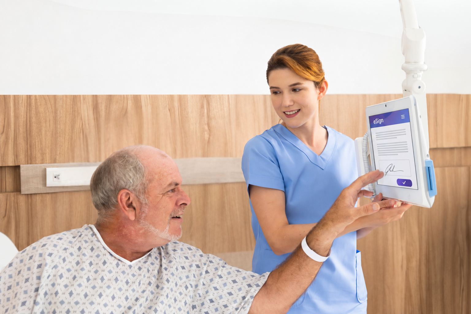 A nurse and a patient review a consent form on a bedside tablet running eSign.