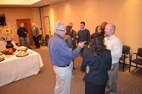 People mingling at a small indoor reception beside a buffet table