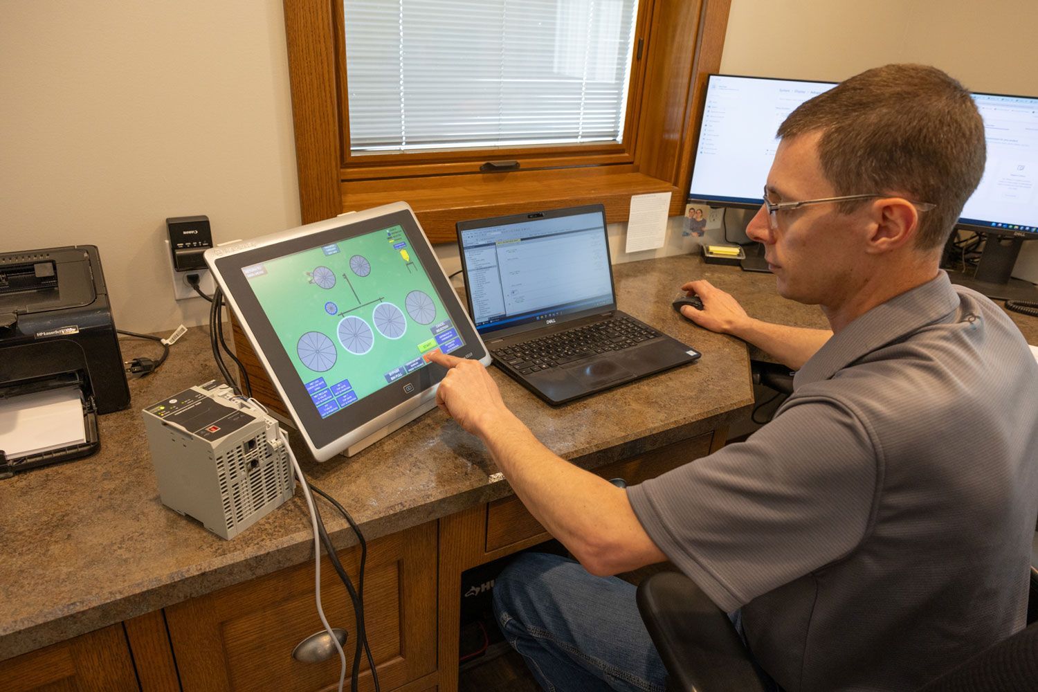 A man is sitting at a desk with a laptop and a monitor.