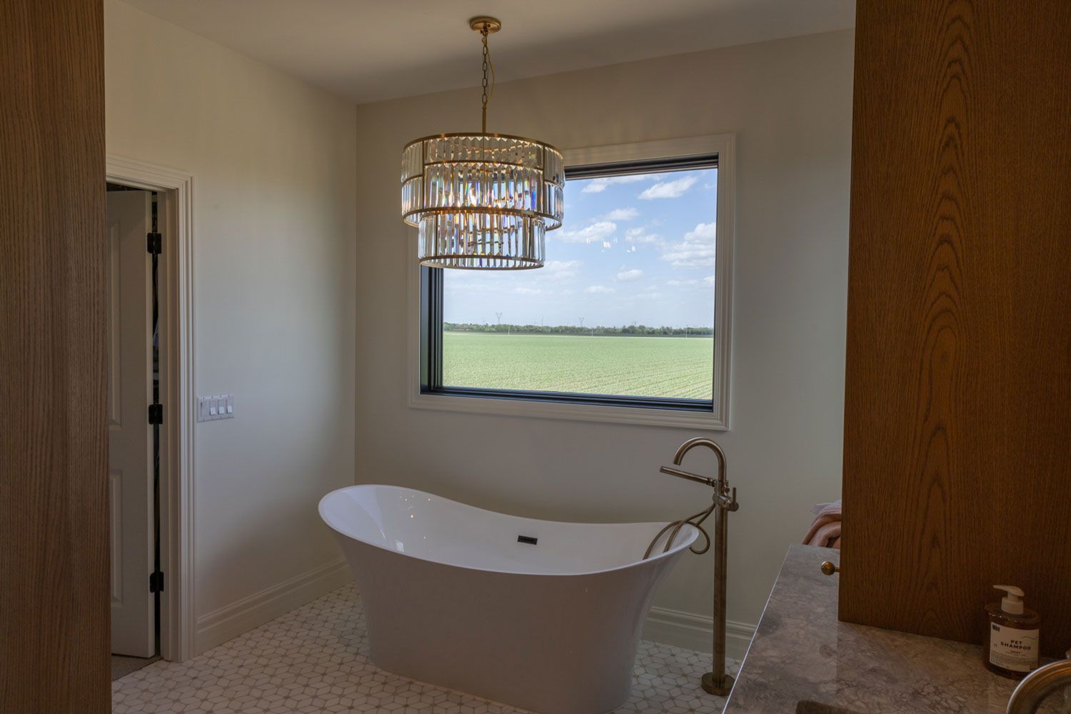 A bathroom with a tub and a window with a chandelier hanging from the ceiling.
