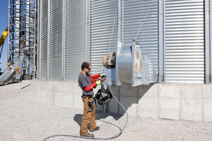 A man is working on a machine outside of a building.