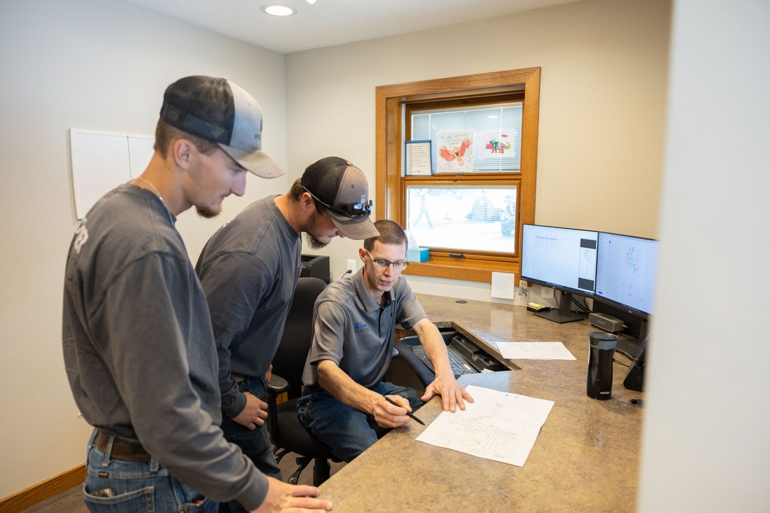 Three men are looking at a piece of paper in an office.