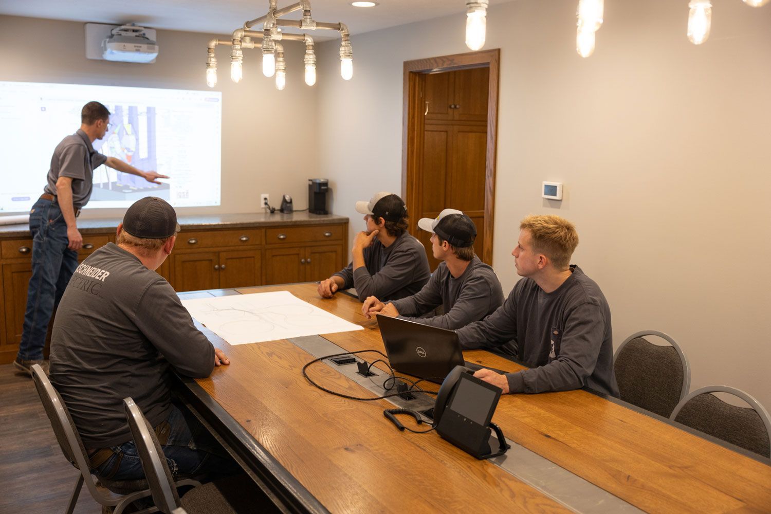 A group of men are sitting at a long wooden table in a conference room.