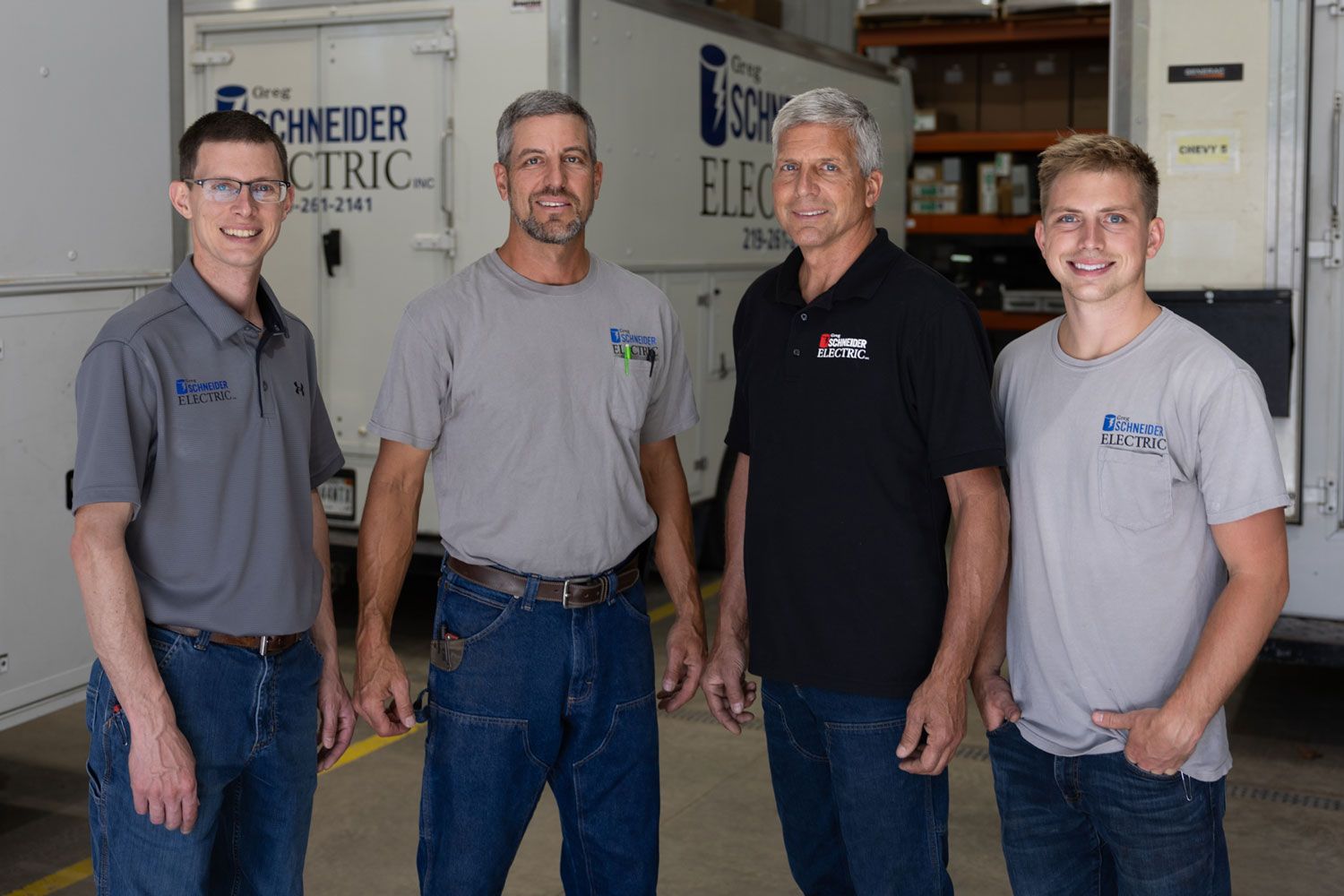 Four men are posing for a picture in front of a schneider electric truck.