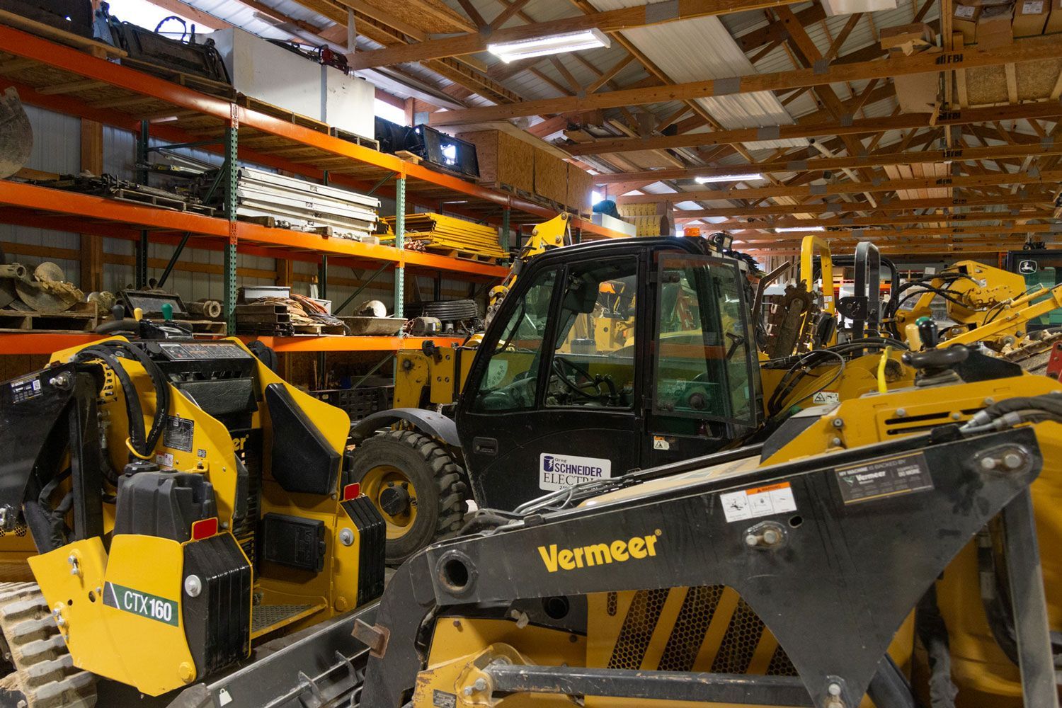 A warehouse filled with lots of machinery including a vermeer tractor