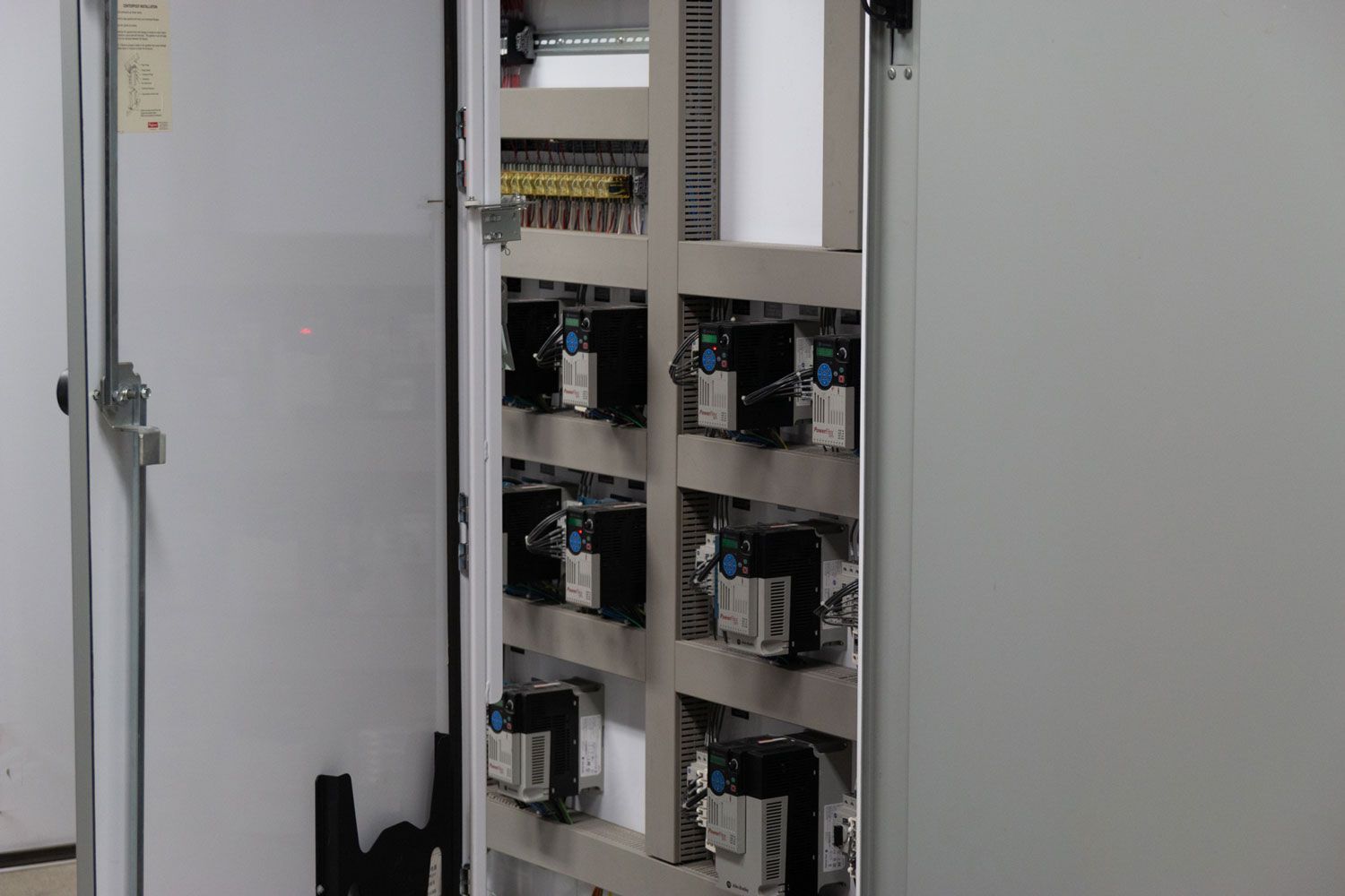 A white cabinet with a lot of electrical equipment inside of it.
