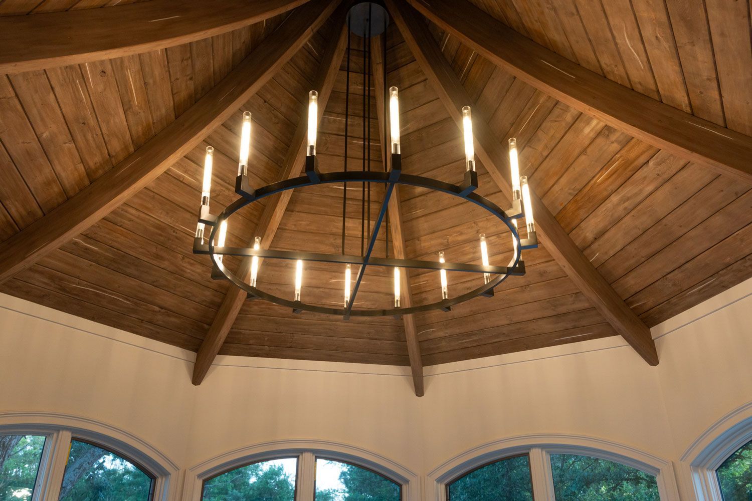 A chandelier is hanging from the ceiling of a wooden gazebo.