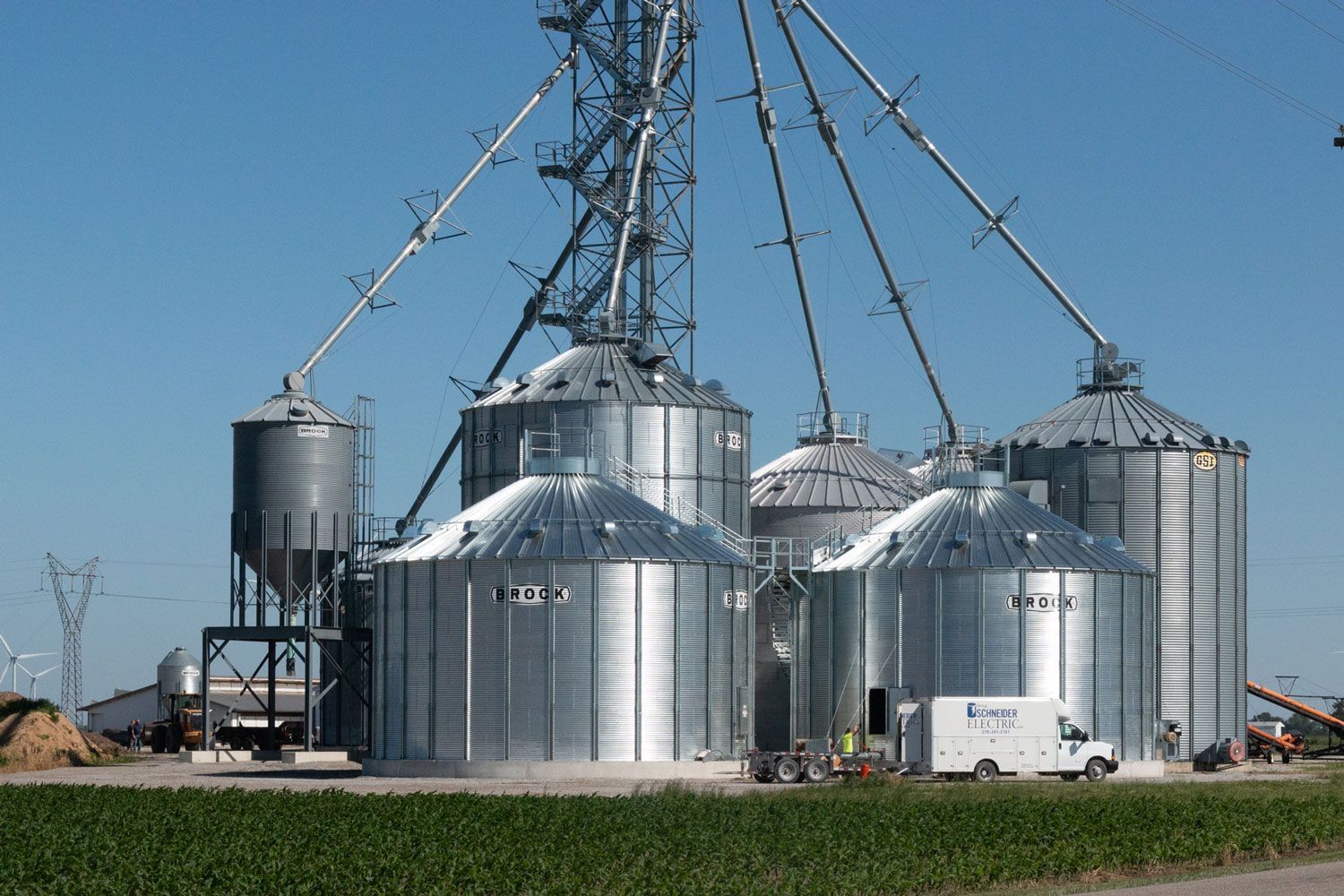 A white truck is parked in front of a grain silo