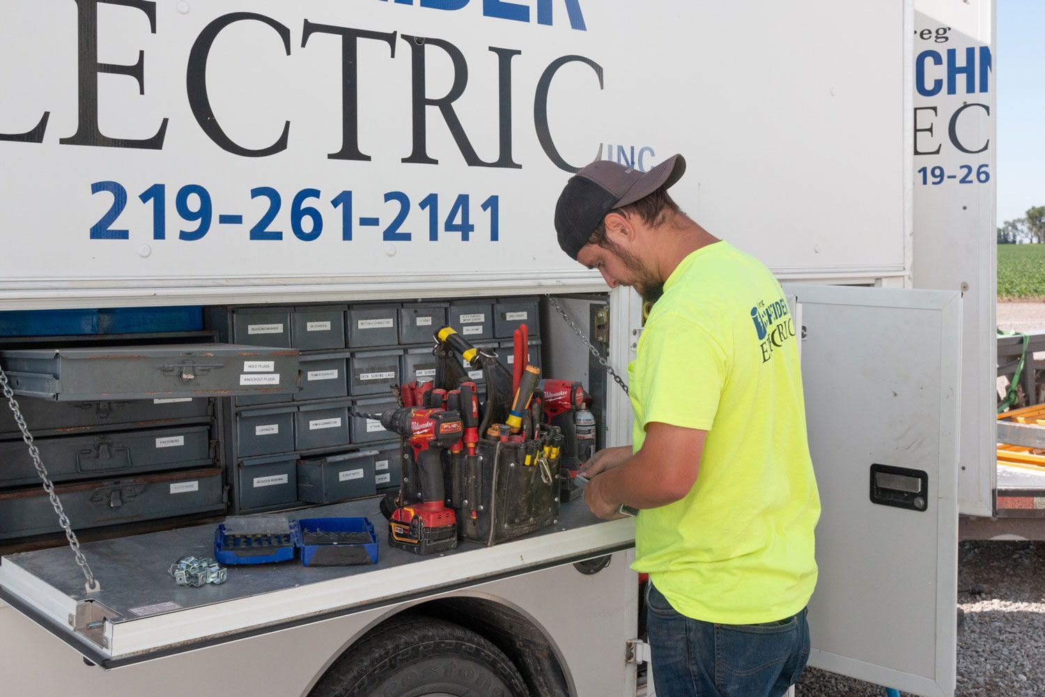 A man in a yellow shirt is working on an electric truck.