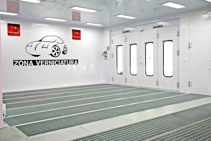 Locale industriale pulito con pareti bianche, griglie sul pavimento e una porta con la scritta