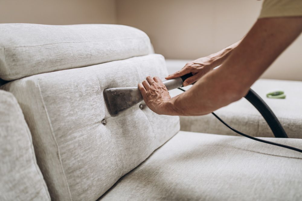 A Person Is Cleaning A Couch With A Vacuum Cleaner — Mr Steam Clean Tweed Coast In Banora Point, NSW