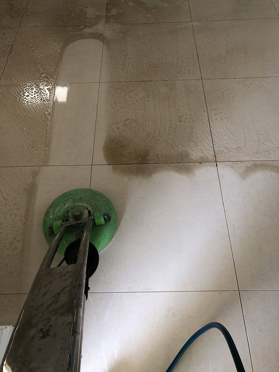 A Person Is Cleaning A Tile Floor With A Machine — Mr Steam Clean Tweed Coast In Banora Point, NSW